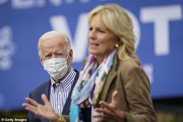 Pictured: Democratic presidential nominee Joe Biden listens as his wife Dr. Jill Biden speaks during a drive-in campaign rally at Bucks County Community College on October 24, 2020 in Bristol, Pennsylvania