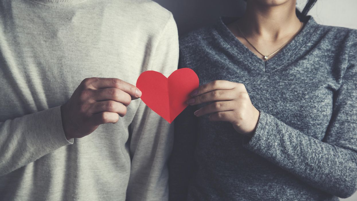 man and woman holding paper heart