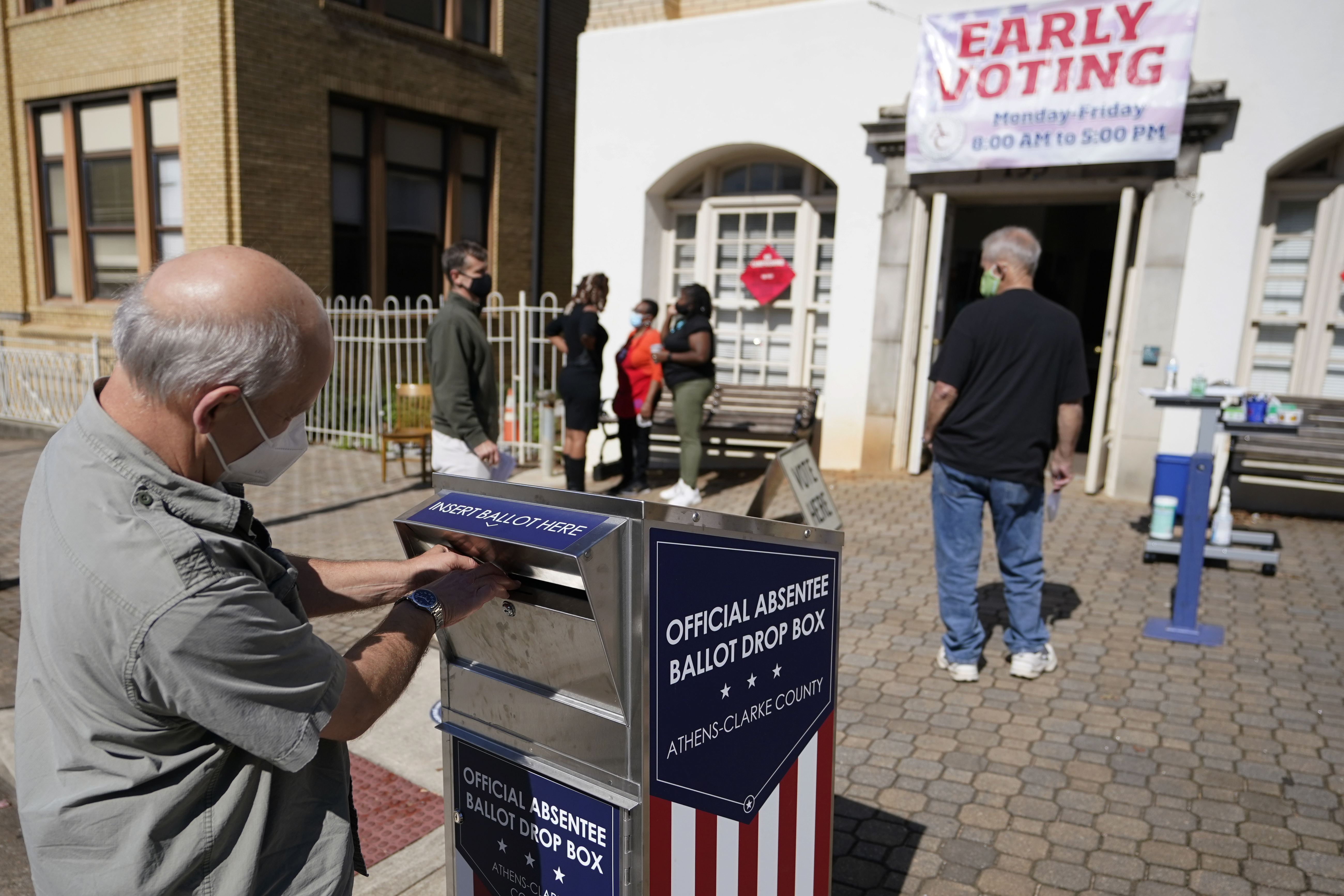 A voter submits a ballot in an official drop box during early voting in October 2020.