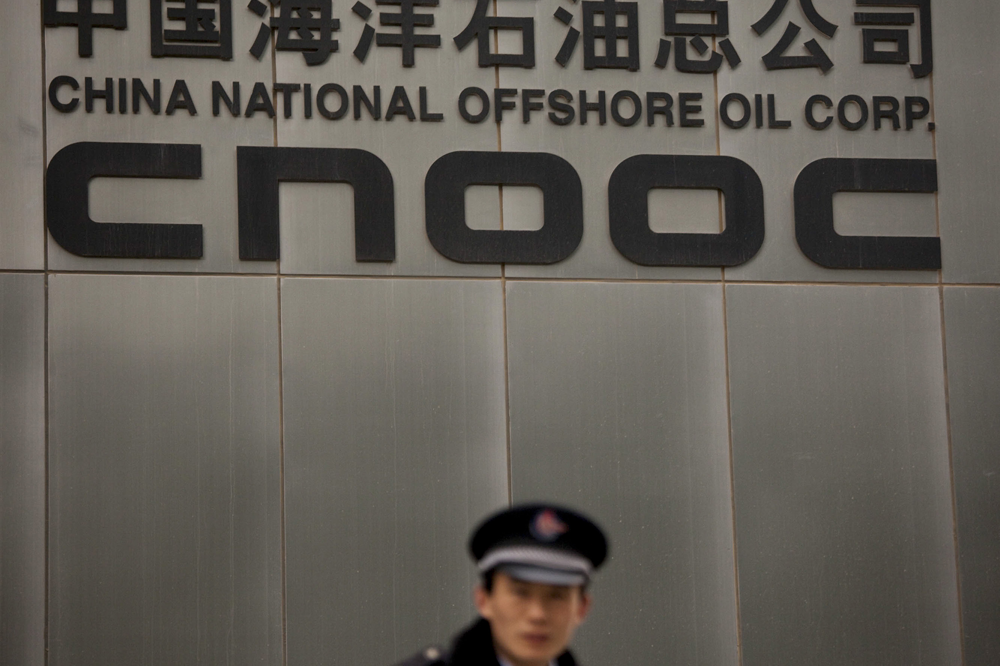 A security guard stands outside the China National Offshore Oil Corp. (CNOOC) Ltd., headquarters in Beijing.