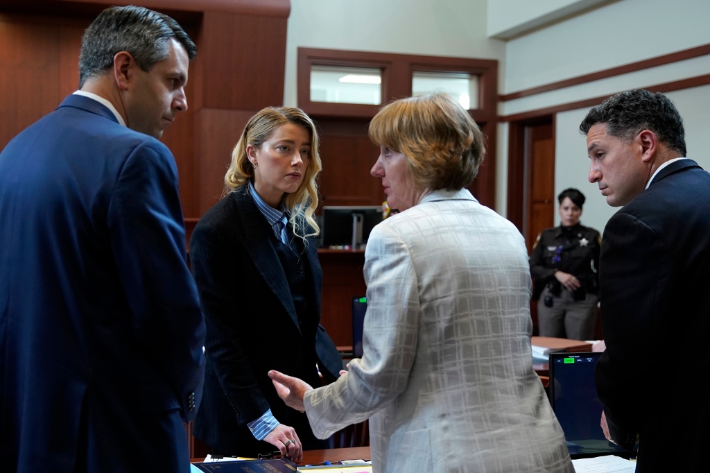 Actor Amber Heard speaks with her legal team during a lunch break at the Fairfax County Circuit Court in Fairfax, Va., Wednesday May 4, 2022.