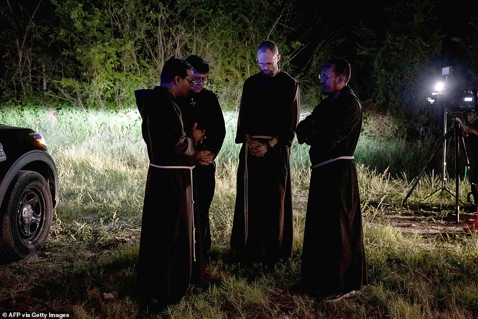 Local priests from the San Antonio Archdiocese stand near the scene where a tractor-trailer was discovered with migrants inside outside San Antonio