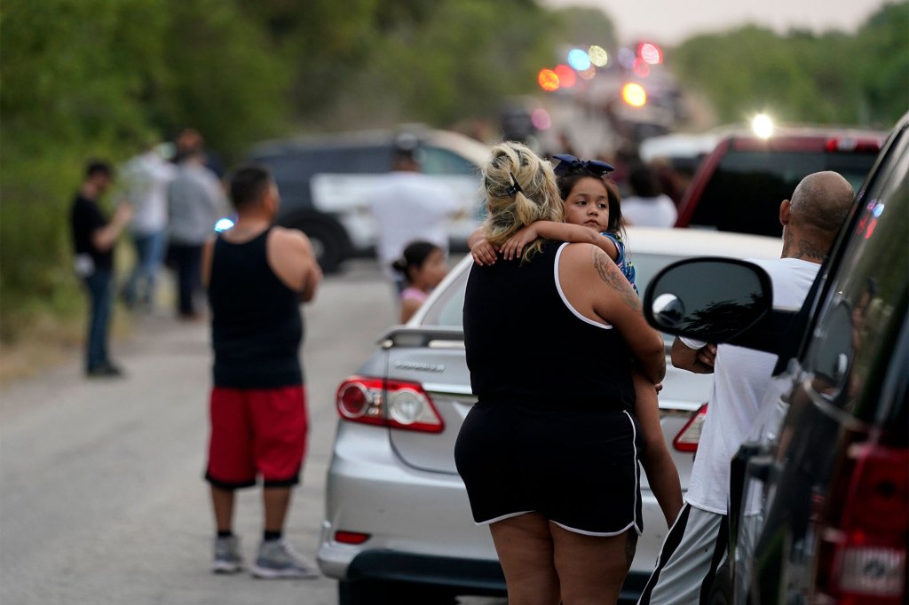 Onlookers stand near the scene where a semitrailer with multiple dead bodies was discovered
