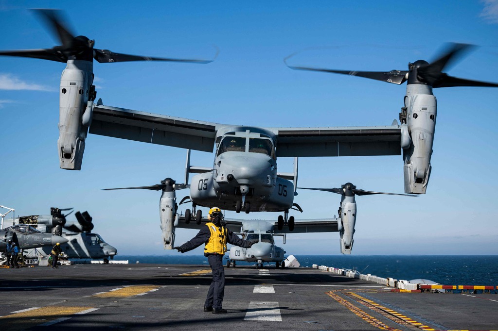 Aviation Boatswains Mate signals to the pilots of the MV-22 Osprey assault support aircraft.