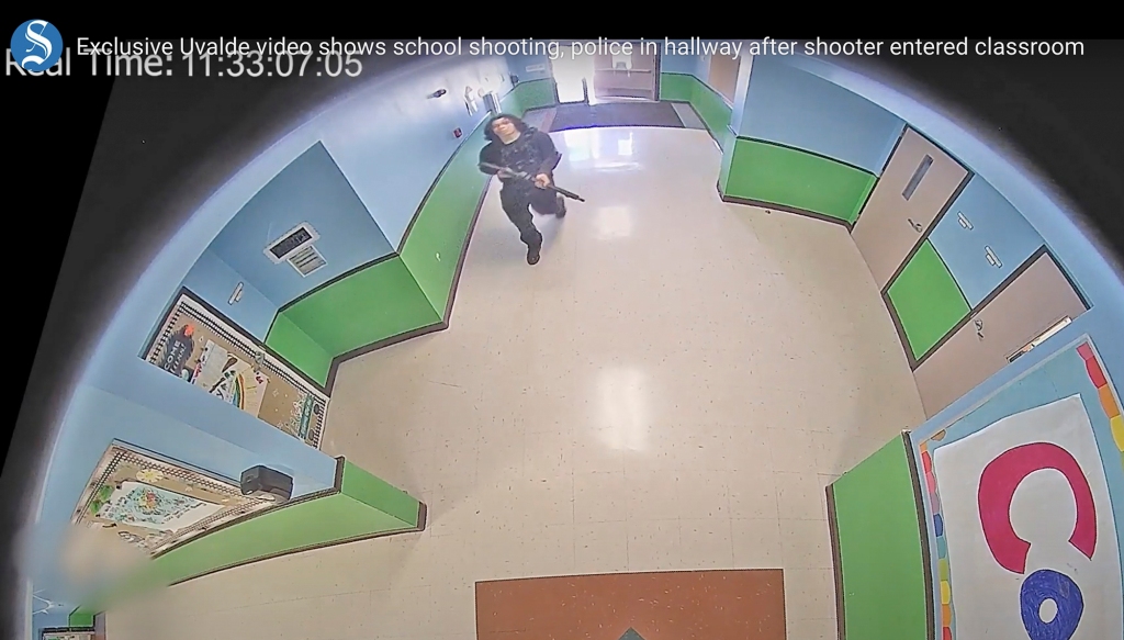 A gunman carrying an AR-15 style rifle enters and walks down a hallway at Robb Elementary School in Uvalde, Texas, Tuesday, May 24, 2022.