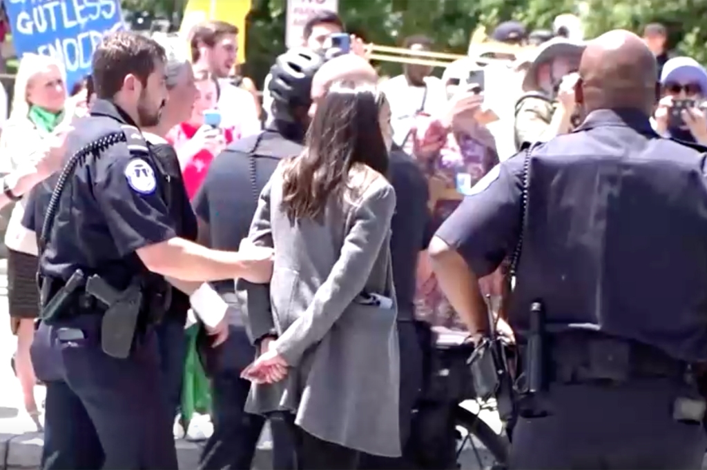 AOC eventually raised a fist to supporters after pretending to be handcuffed.