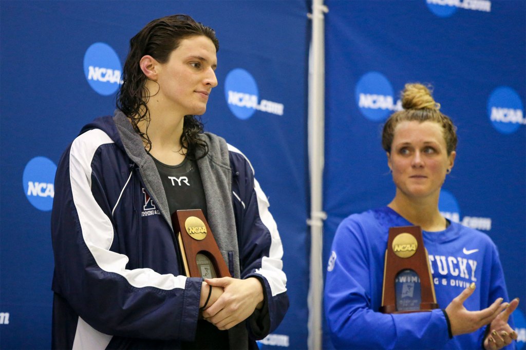 Penn Quakers swimmer Lia Thomas holds a trophy after finishing fifth in the 200 free at the NCAA Swimming & Diving Championships as Kentucky Wildcats swimmer Riley Gaines looks on.