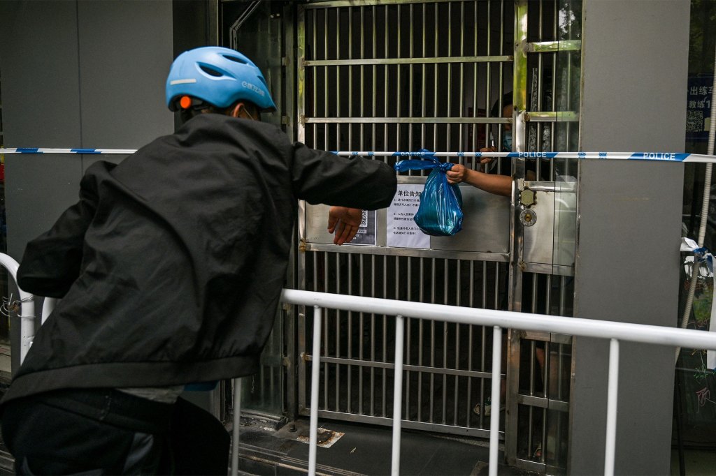 A delivery worker gives food to a man during the coronavirus lockdown in the Jing' an district of Shanghai.