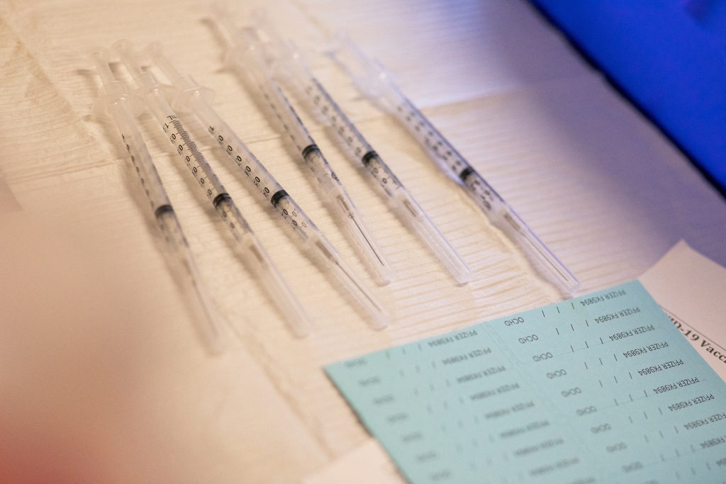 Syringes of COVID-19 vaccine are placed side by side a paper towel.