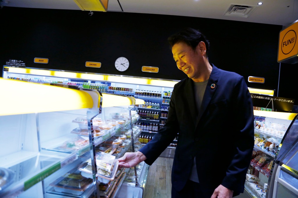FamilyMart Executive Officer Tomohiro Kano looks at a packed lunch at a FamilyMart convenience store.