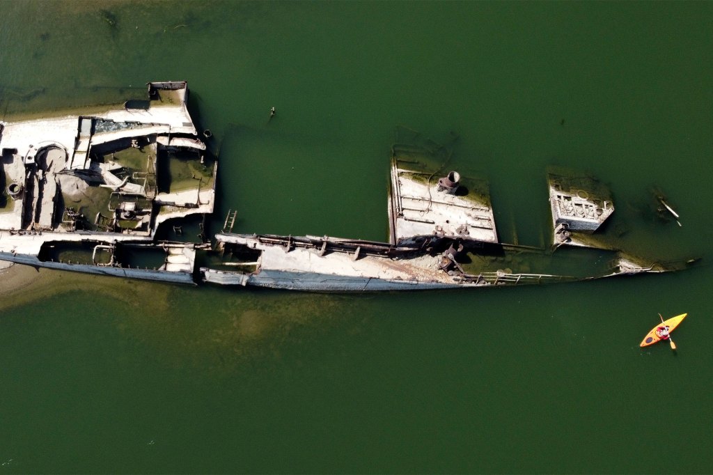 A kayaker paddles by the wreckage of a WWII German warship.