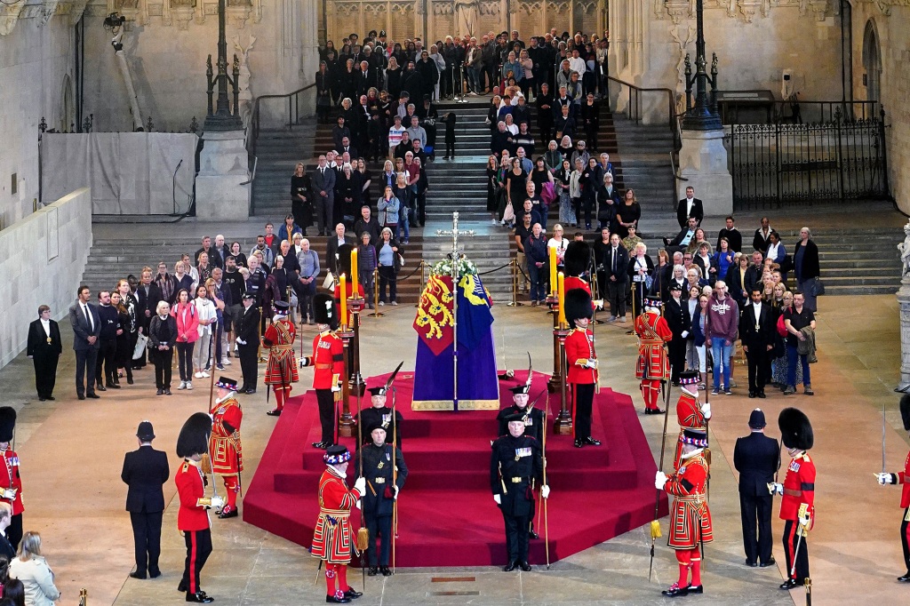 Members of the public file past the coffin of Queen Elizabeth II, draped in the Royal Standard with the Imperial State Crown and the Sovereign's orb and sceptre, lying in state on the catafalque in Westminster Hall, at the Palace of Westminster, London, ahead of her funeral on Monday. - Queen Elizabeth II will lie in state in Westminster Hall inside the Palace of Westminster, until 0530 GMT on September 19, a few hours before her funeral, with huge queues expected to file past her coffin to pay their respects. (Photo by Yui Mok / POOL / AFP) (Photo by YUI MOK/POOL/AFP via Getty Images)